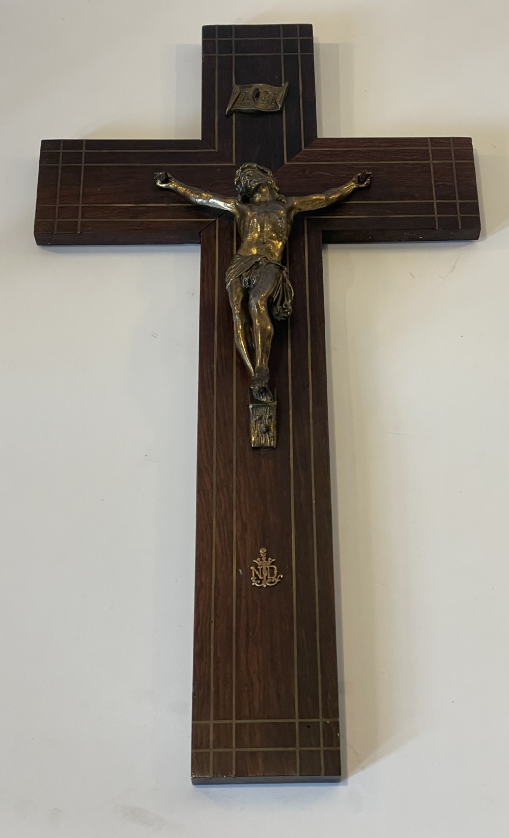 A dark rosewood wall crucifix featuring brass linear inlay, an ornate INRI plaque, a gilt metal figure of Christ, and a monogram emblem near the base.