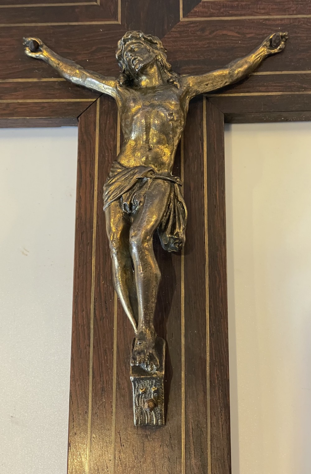 A dark rosewood wall crucifix featuring brass linear inlay, an ornate INRI plaque, a gilt metal figure of Christ, and a monogram emblem near the base. View II