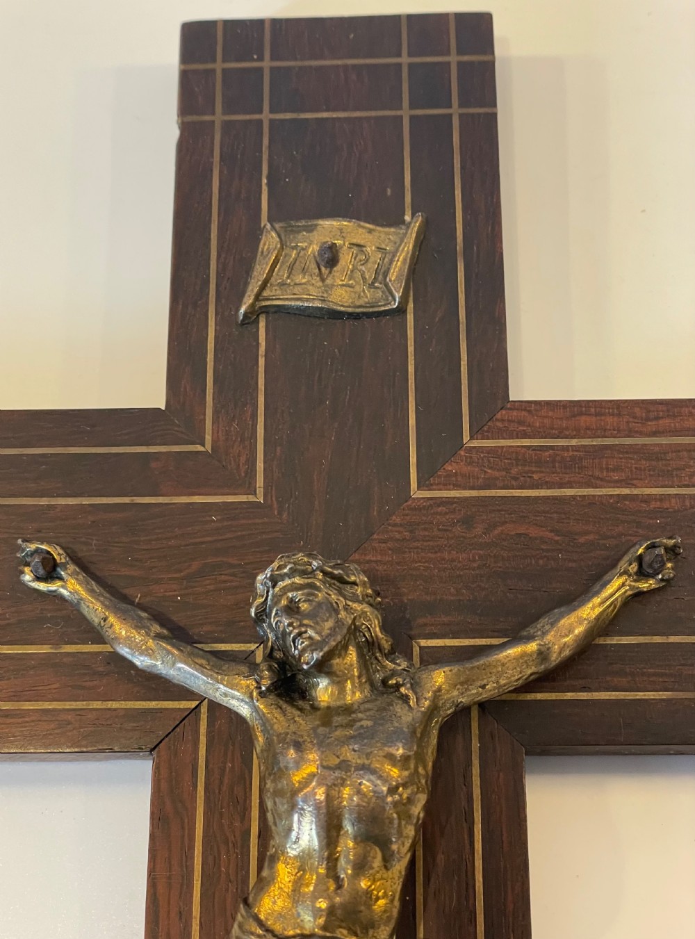 A dark rosewood wall crucifix featuring brass linear inlay, an ornate INRI plaque, a gilt metal figure of Christ, and a monogram emblem near the base. View IV