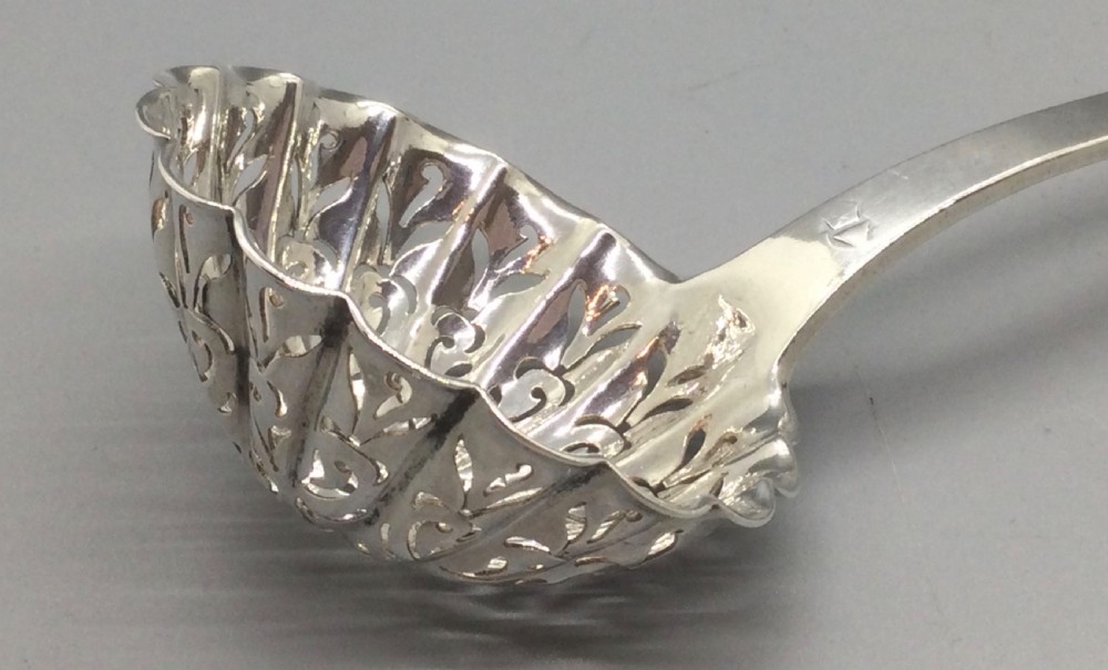 A nineteenth-century French silver sifter spoon featuring a scalloped pierced bowl and smooth curved handle. View IX