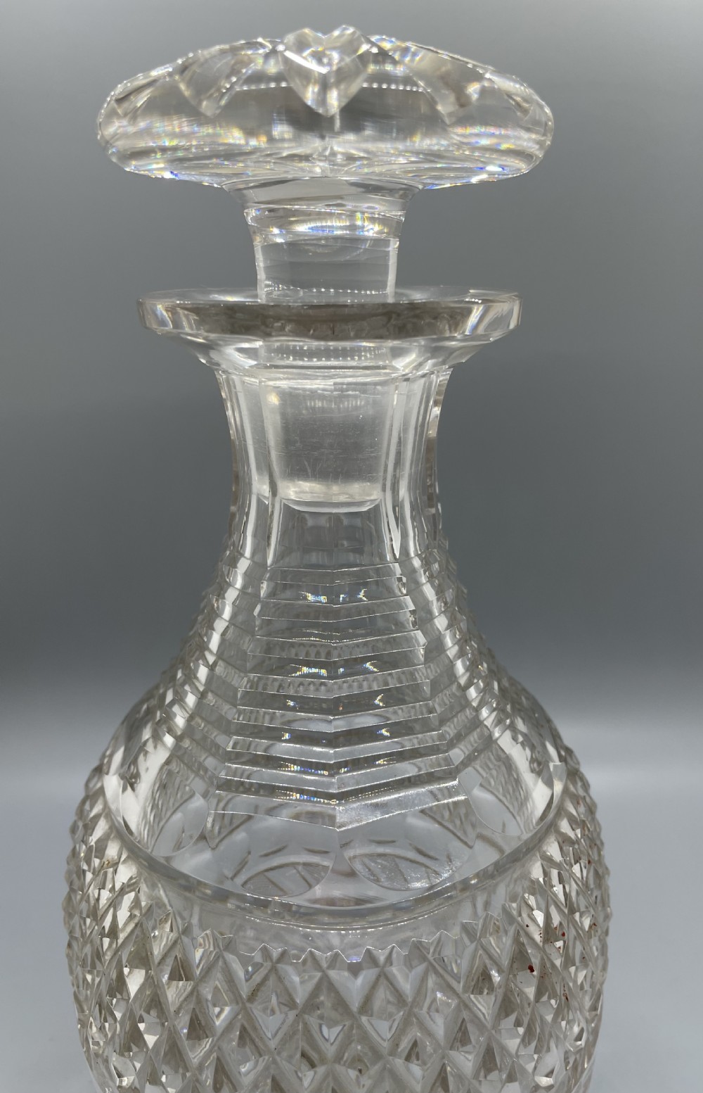 A clear cut lead crystal decanter featuring diamond cutting, a ringed neck, and a star-cut flat stopper. View III