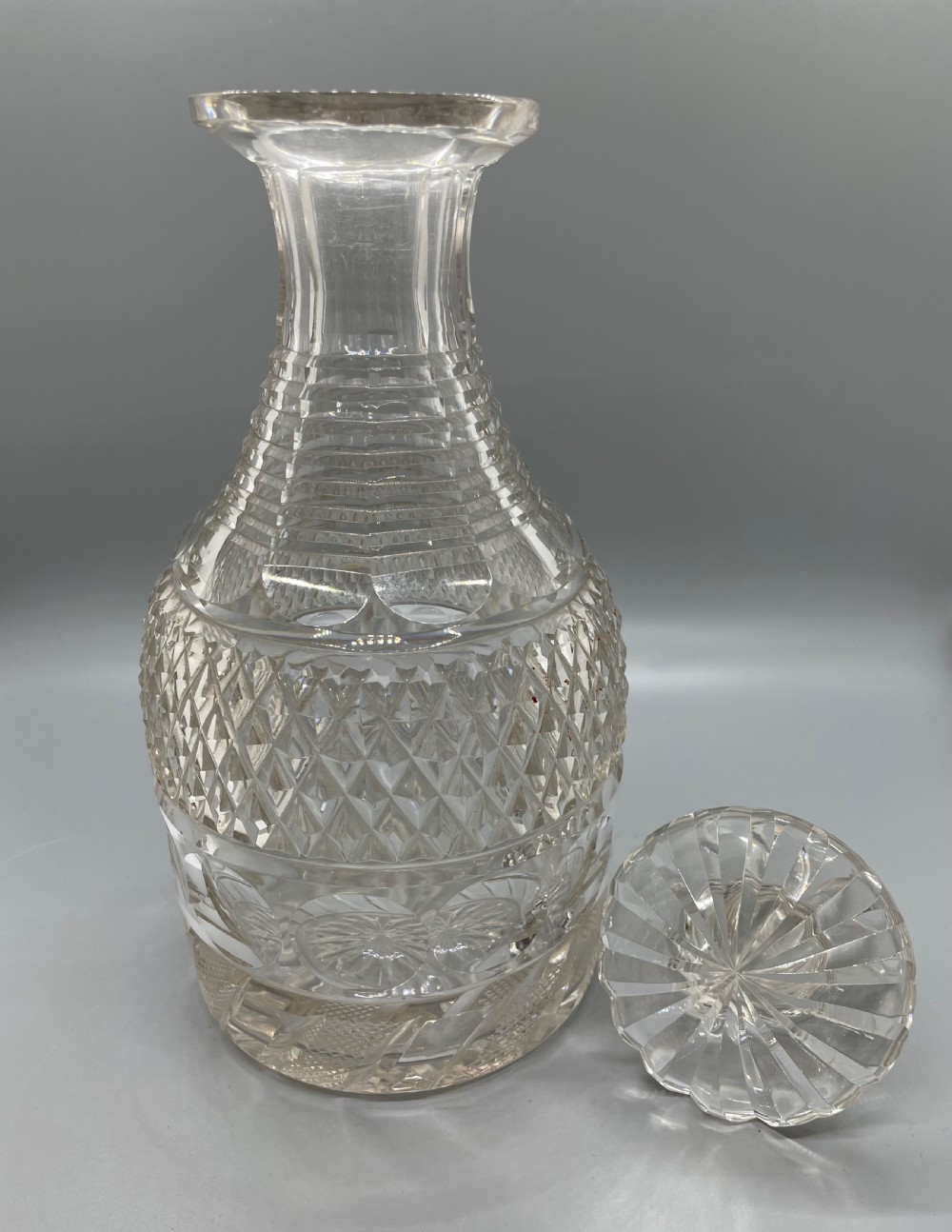 A clear cut lead crystal decanter featuring diamond cutting, a ringed neck, and a star-cut flat stopper. View IV