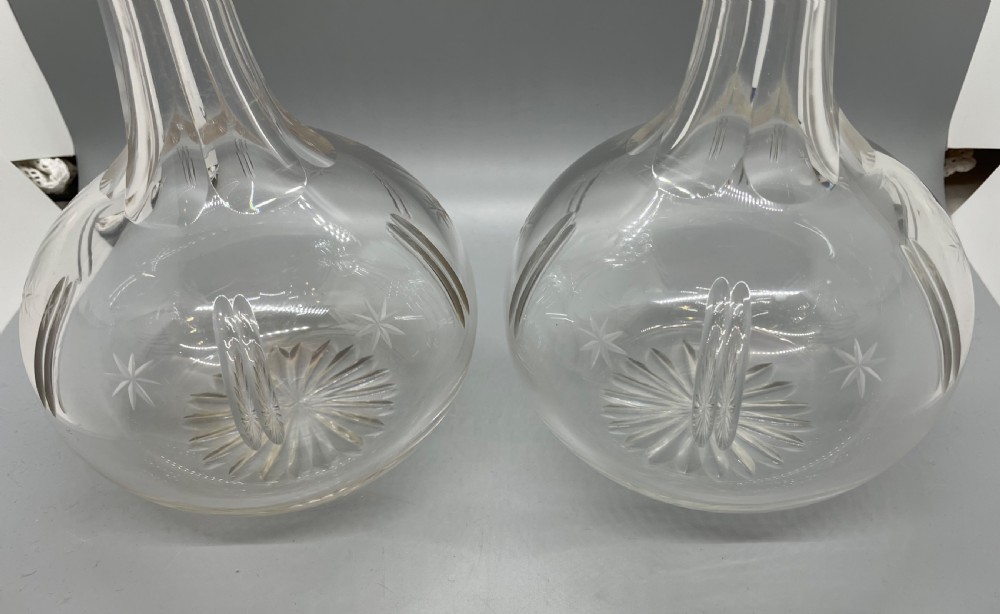 A pair of Victorian clear cut crystal decanters featuring starburst geometric engravings, fluted necks, and matching round cut glass stoppers. View III