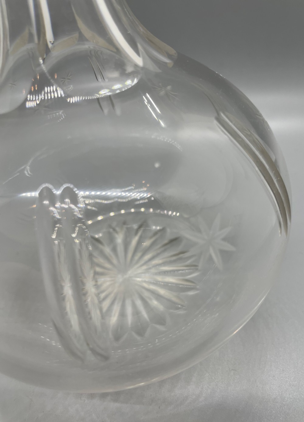 A pair of Victorian clear cut crystal decanters featuring starburst geometric engravings, fluted necks, and matching round cut glass stoppers. View VIII