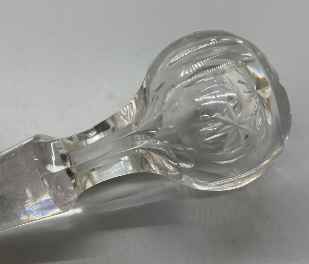 A pair of Victorian clear cut crystal decanters featuring starburst geometric engravings, fluted necks, and matching round cut glass stoppers. View IX