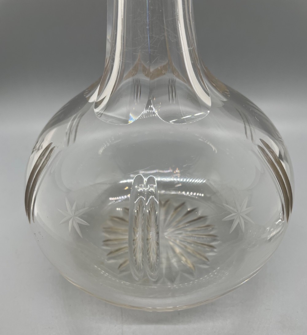 A pair of Victorian clear cut crystal decanters featuring starburst geometric engravings, fluted necks, and matching round cut glass stoppers. View XIII