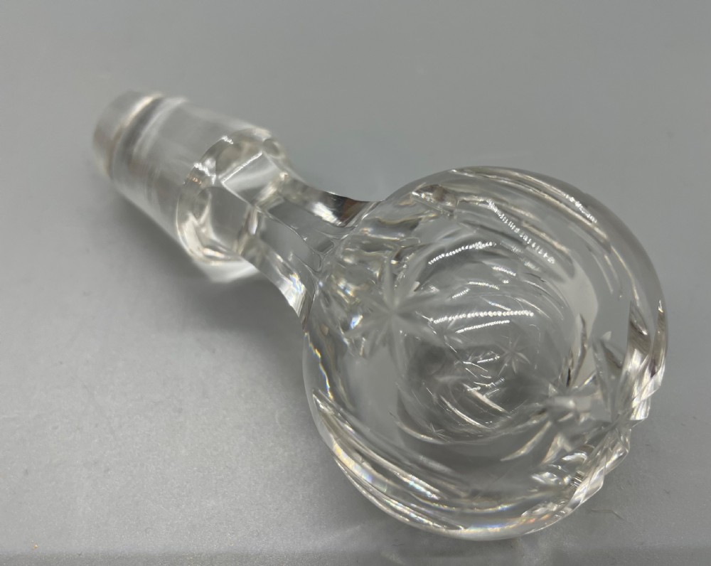 A pair of Victorian clear cut crystal decanters featuring starburst geometric engravings, fluted necks, and matching round cut glass stoppers. View XV