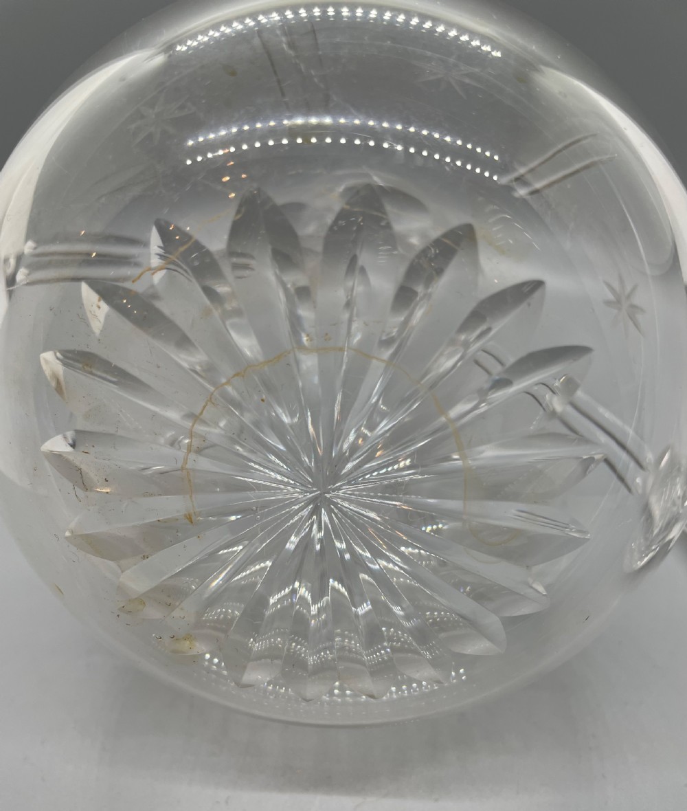 A pair of Victorian clear cut crystal decanters featuring starburst geometric engravings, fluted necks, and matching round cut glass stoppers. View XVI