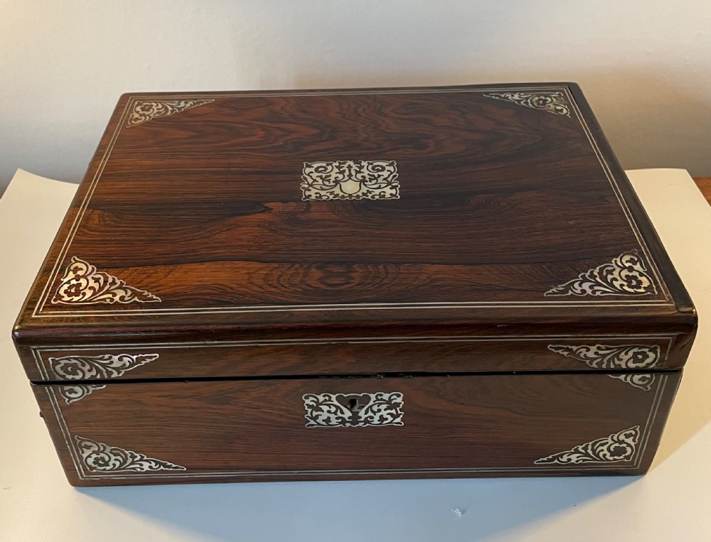 A dark brown rosewood rectangular writing slope decorated with floral mother of pearl inlay on the corners, lid centre, and lock escutcheon.