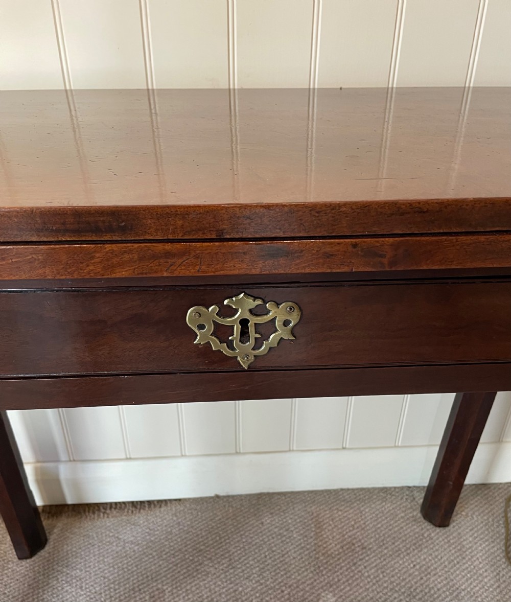 A Georgian mahogany fold-over tea table featuring straight square legs with subtle corner brackets and brass drop handles. View V
