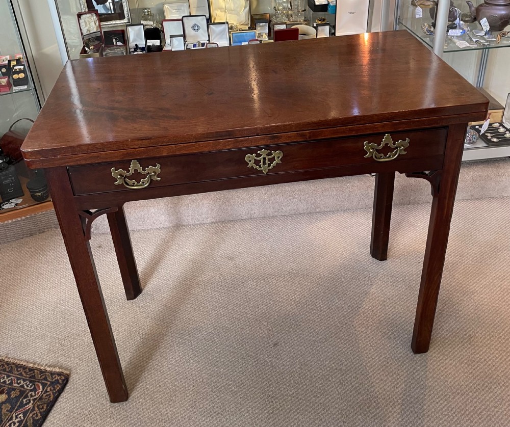 A Georgian mahogany fold-over tea table featuring straight square legs with subtle corner brackets and brass drop handles. View VII