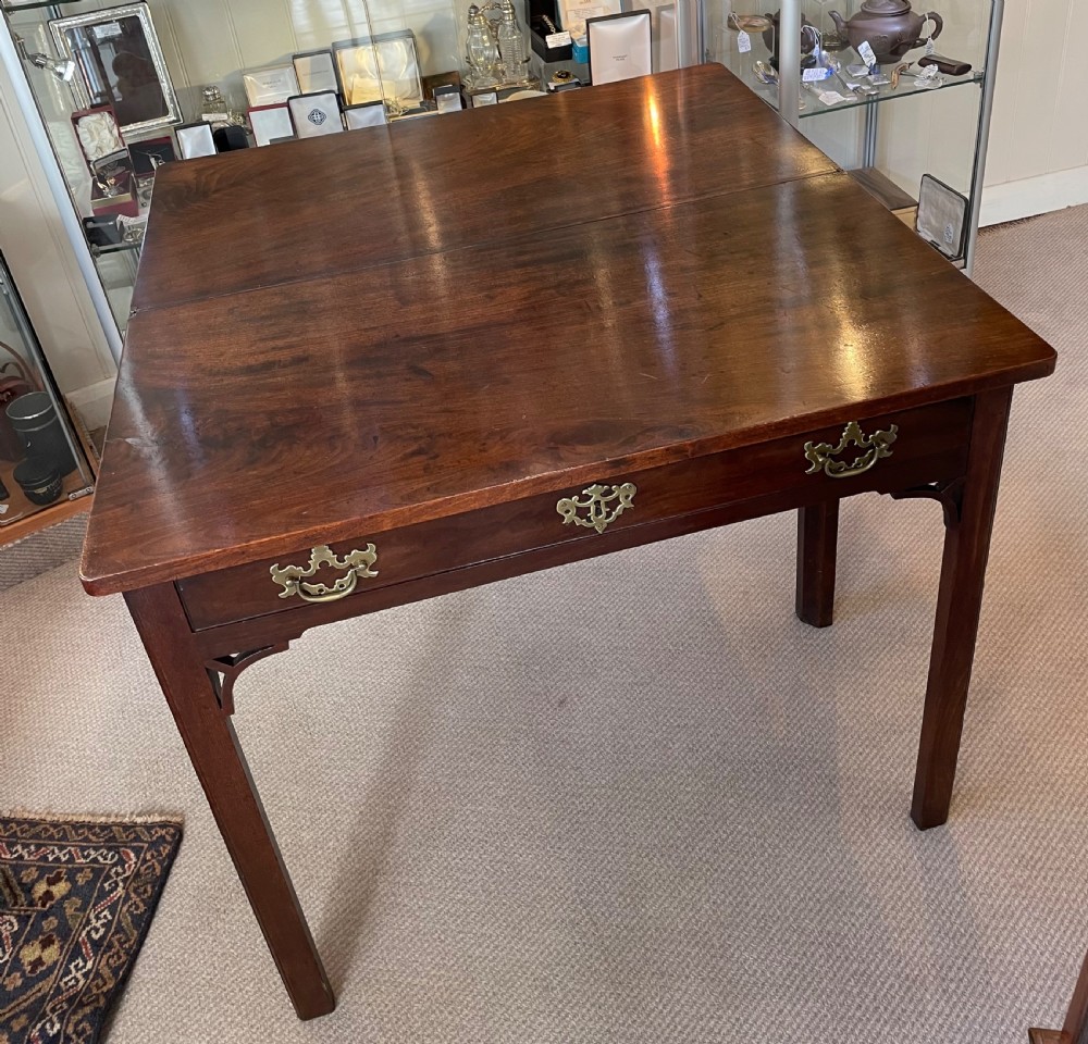 A Georgian mahogany fold-over tea table featuring straight square legs with subtle corner brackets and brass drop handles. View X
