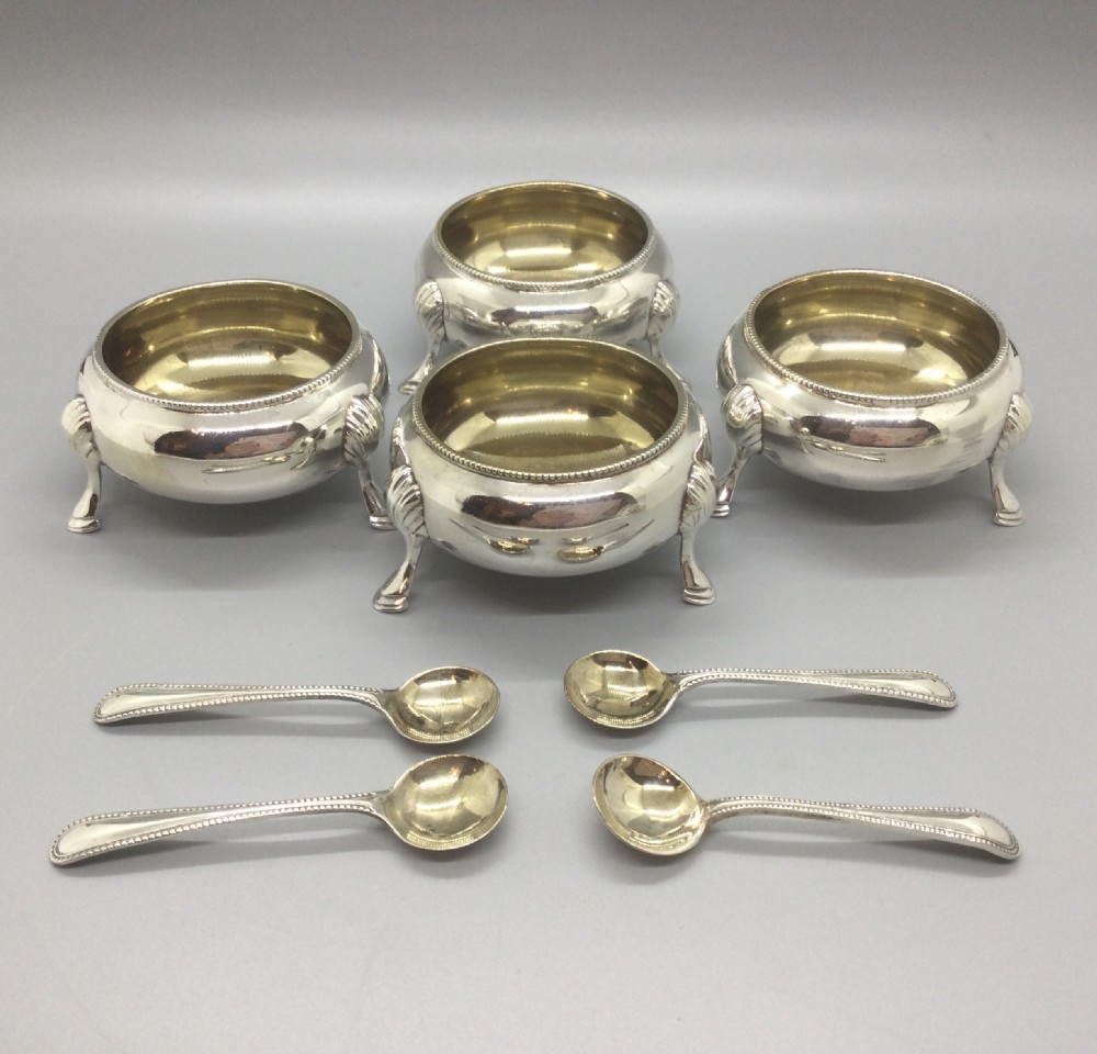 A set of four Victorian sterling silver open salt cellars with gilt interiors and shell-capped feet, displayed in a velvet-lined case with spoons. View IV