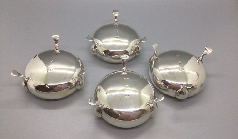 A set of four Victorian sterling silver open salt cellars with gilt interiors and shell-capped feet, displayed in a velvet-lined case with spoons. View VII