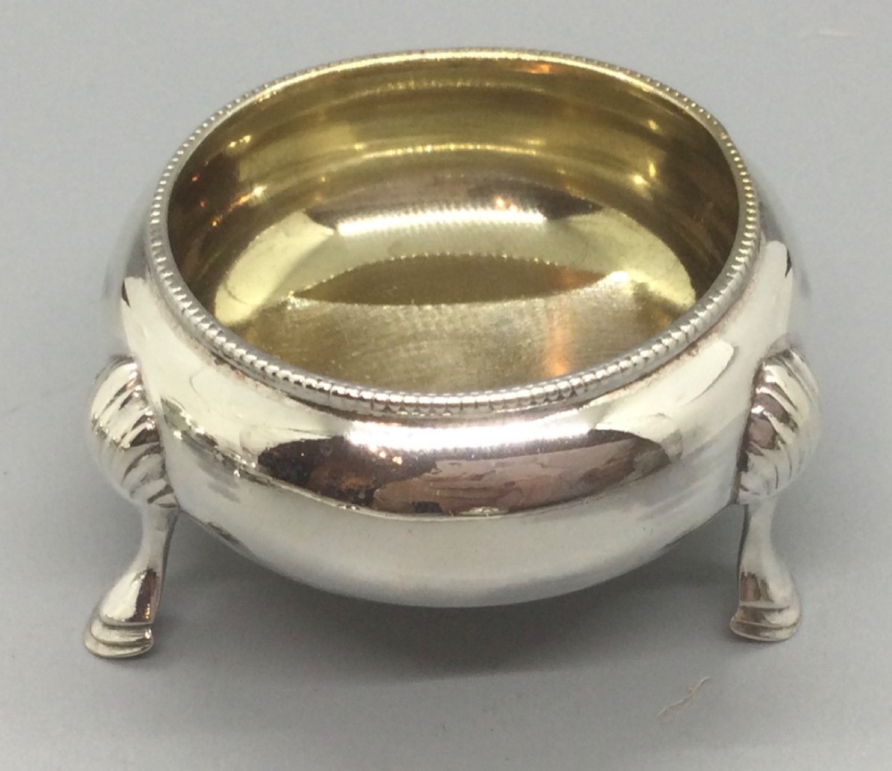 A set of four Victorian sterling silver open salt cellars with gilt interiors and shell-capped feet, displayed in a velvet-lined case with spoons. View XI