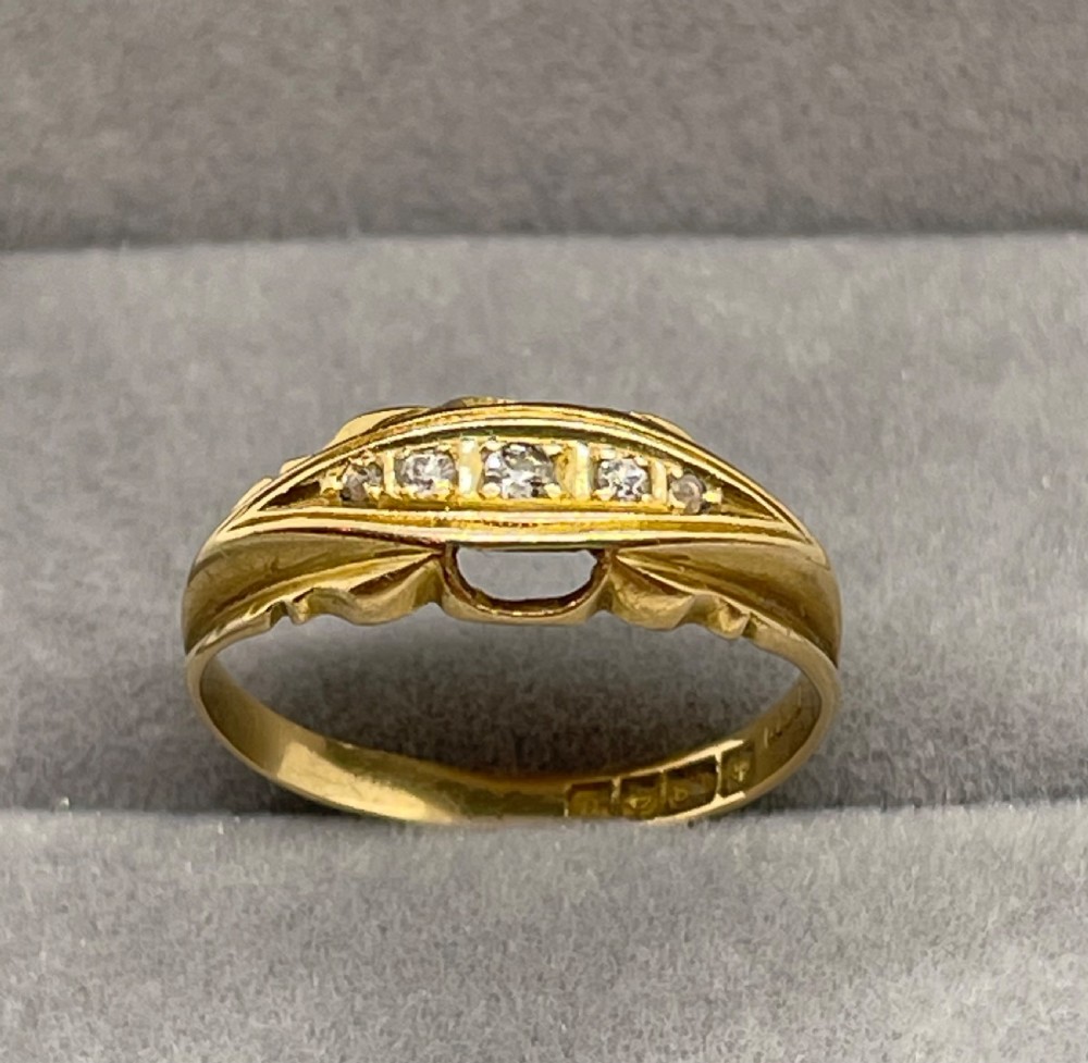 An antique 18ct yellow gold ring featuring a row of inset diamonds set within a carved boat-shaped head.