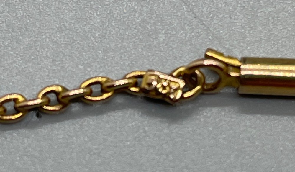 An Edwardian 9ct gold circular openwork pendant set with seed pearls and round faceted peridots, featuring a hanging drop gemstone and attached chain. View VIII