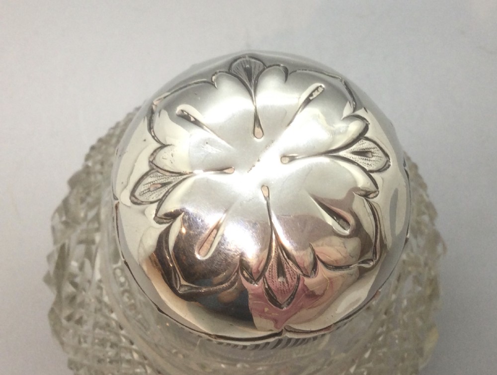 A globular cut glass perfume bottle featuring a faceted diamond pattern and an embossed sterling silver top. View VII