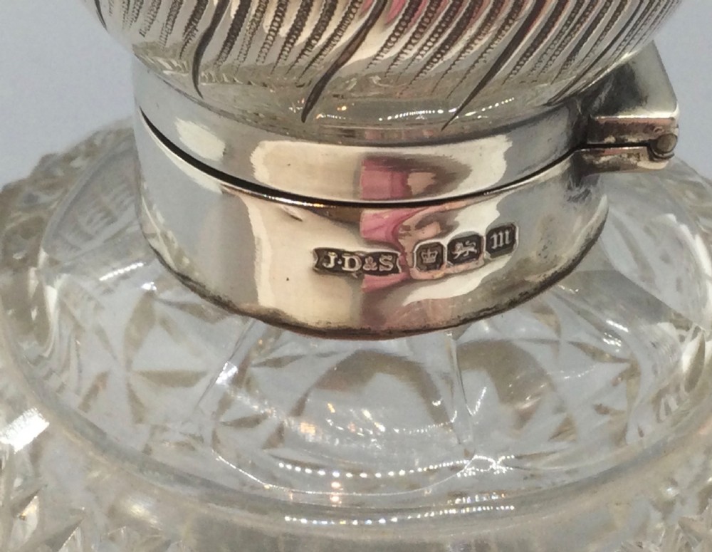 A globular cut glass perfume bottle featuring a faceted diamond pattern and an embossed sterling silver top. View VIII