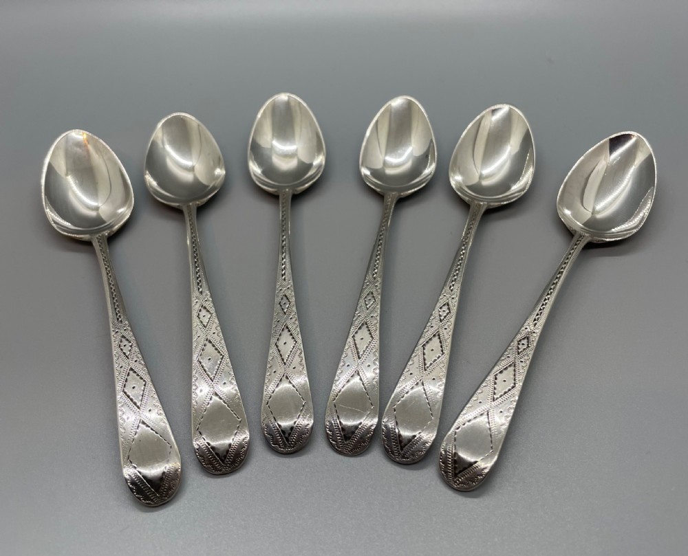 A set of six 18th-century George III sterling silver teaspoons with bright-cut lattice engraving along the handles.