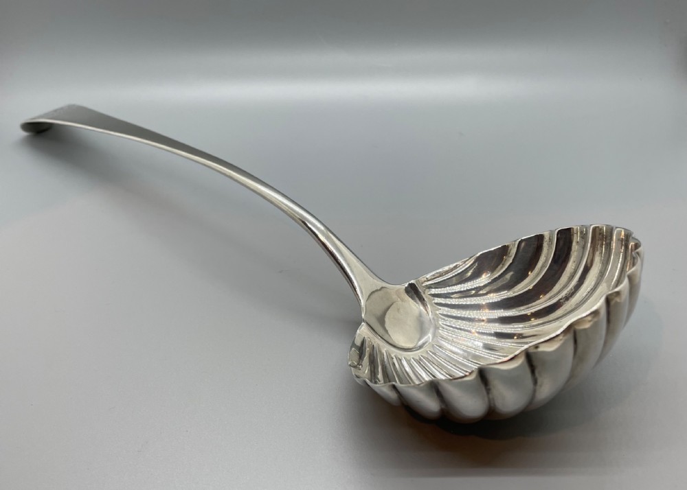 An 18th-century sterling silver soup ladle featuring a fluted shell-shaped bowl and an engraved curved handle terminal. View II