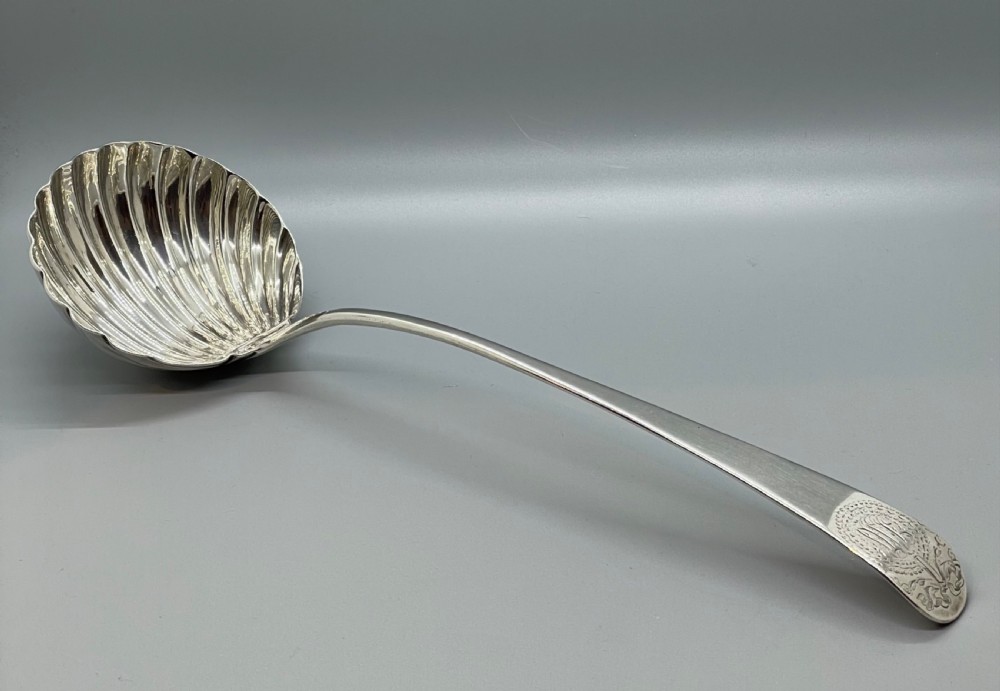 An 18th-century sterling silver soup ladle featuring a fluted shell-shaped bowl and an engraved curved handle terminal. View XI