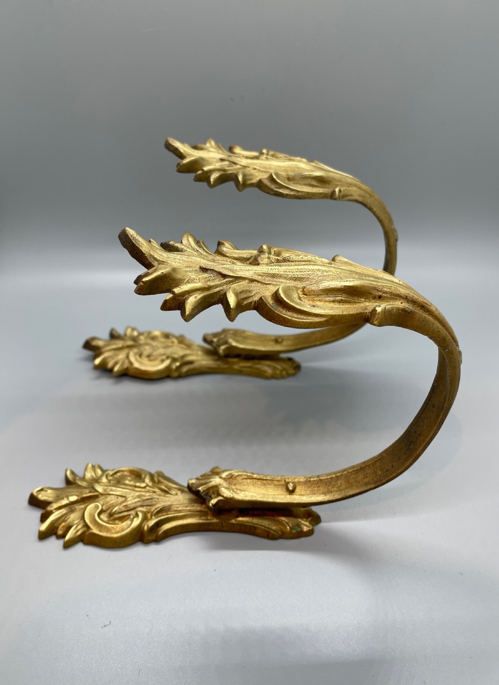A pair of late nineteenth-century French ormolu curtain tie backs shaped as sweeping acanthus leaves with a gold gilded finish.