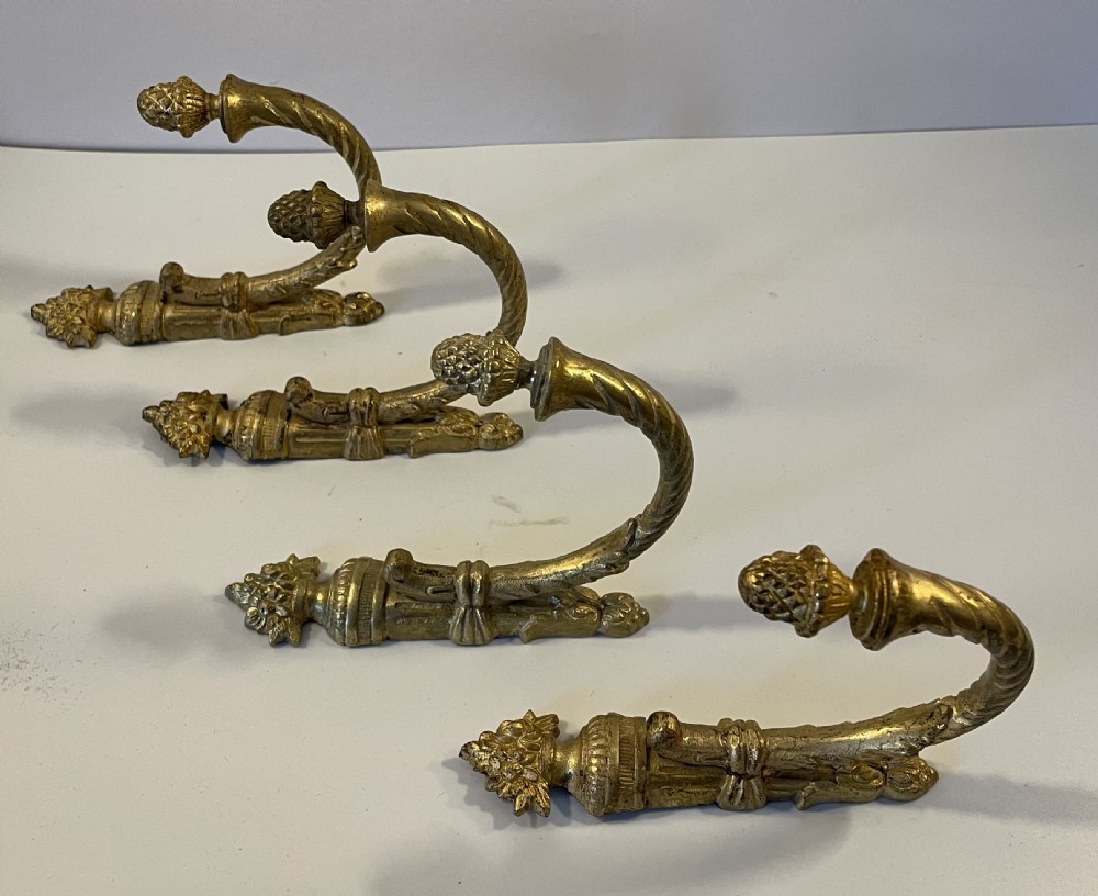 A set of four 19th-century French ormolu curtain tie backs with pinecone finials, fluted arms, and wall-mount backplates. View II