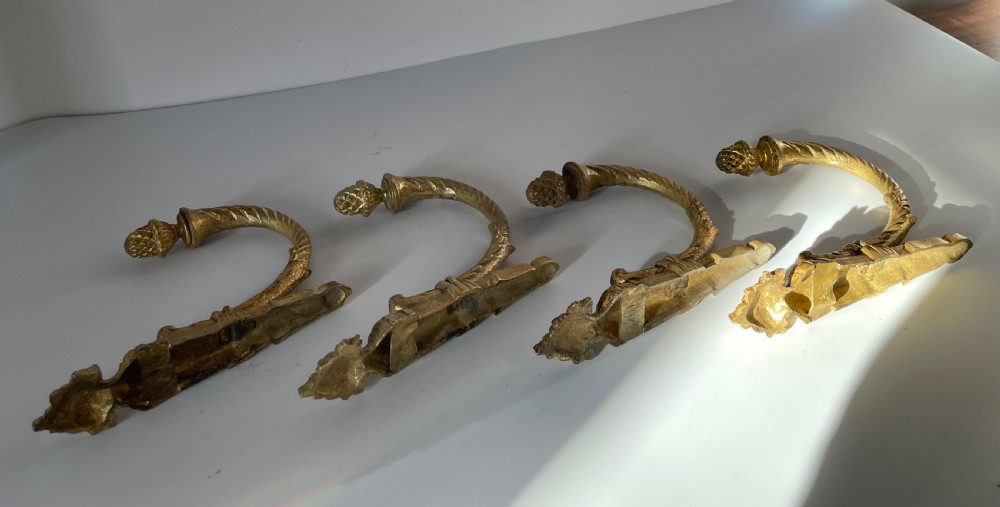 A set of four 19th-century French ormolu curtain tie backs with pinecone finials, fluted arms, and wall-mount backplates. View VIII