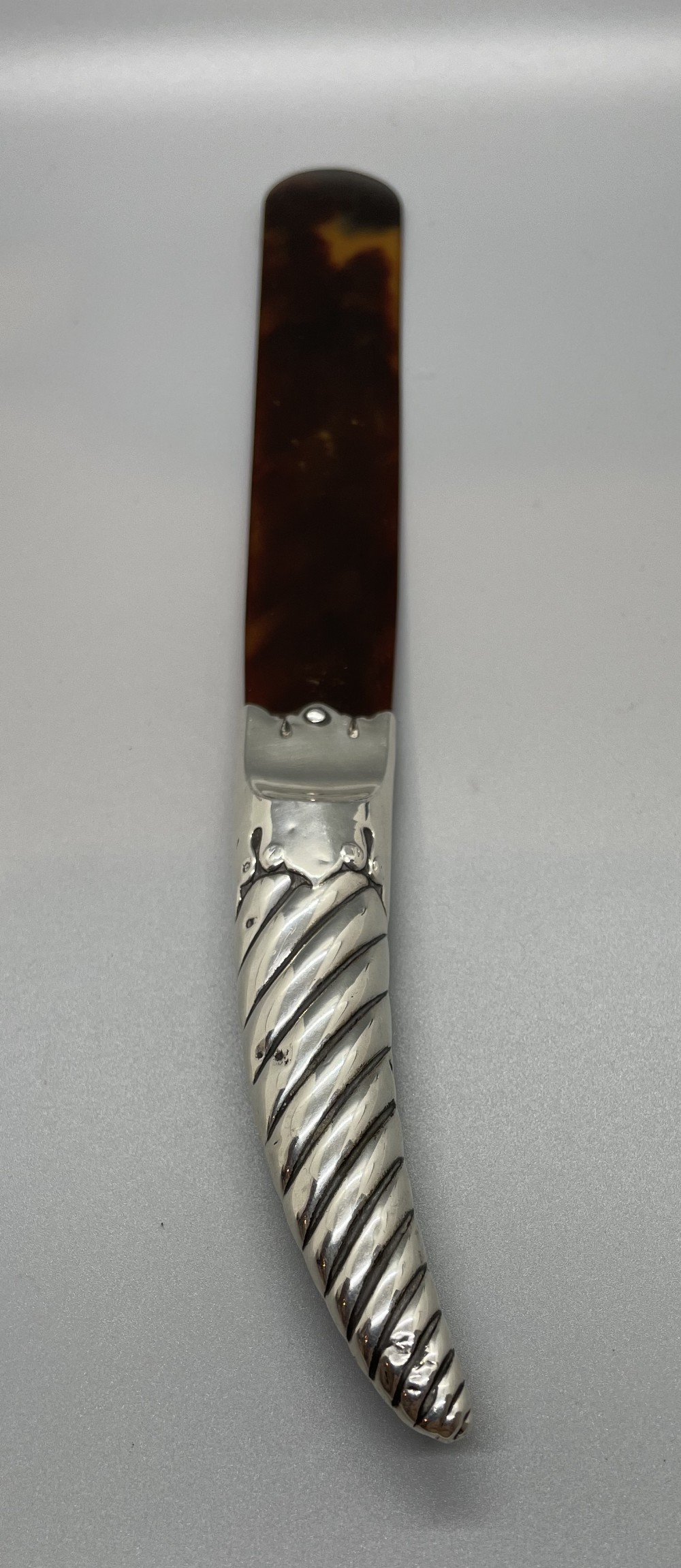 A Victorian letter opener with a spiral-fluted silver handle and a dark brown tortoiseshell blade.