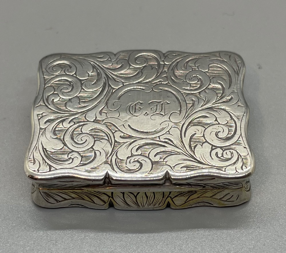 An early Victorian rectangular sterling silver vinaigrette box with scrollwork engraving, shaped edges, and a central monogrammed cartouche. View III