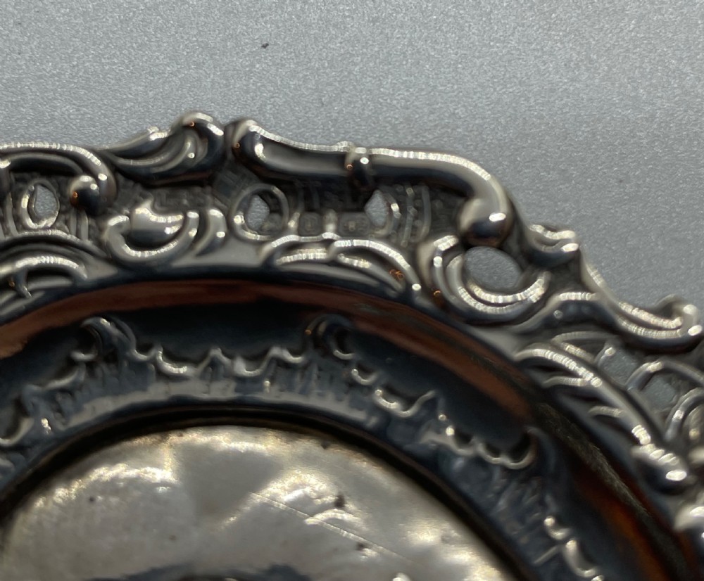 A late Victorian heart-shaped sterling silver trinket dish featuring an embossed central motif of cherub heads amongst clouds with a pierced scroll border. View IV
