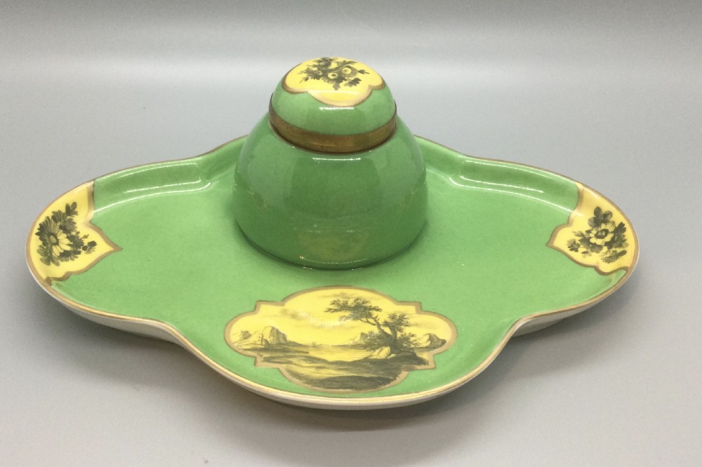 An early 19th-century green and yellow porcelain inkstand featuring a central dome inkwell and hand-painted landscape reserves on a shaped tray.