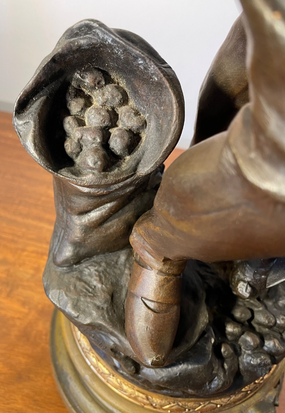 A dark patinated bronze figure depicting a standing woodsman holding an axe on a circular cast base with a named plaque. View VIII