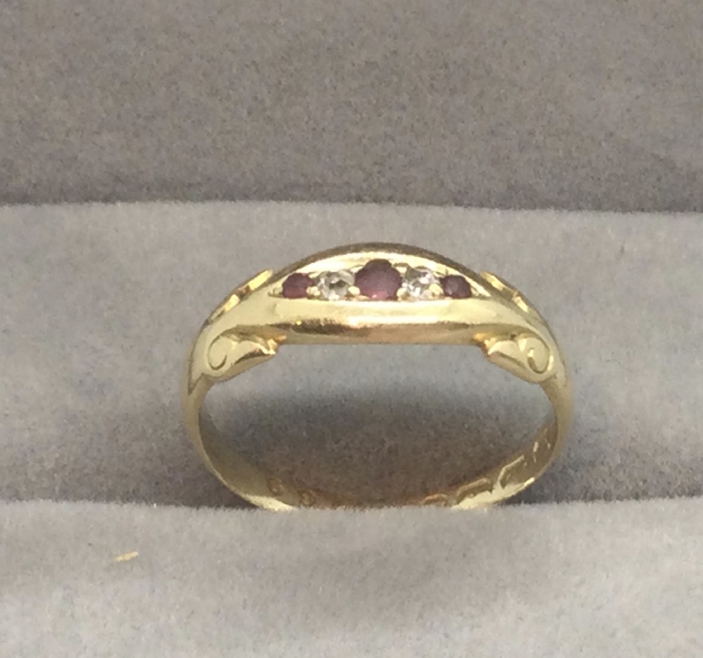 A Victorian 18ct yellow gold ring set with red rubies and small diamonds in a carved boat head setting.