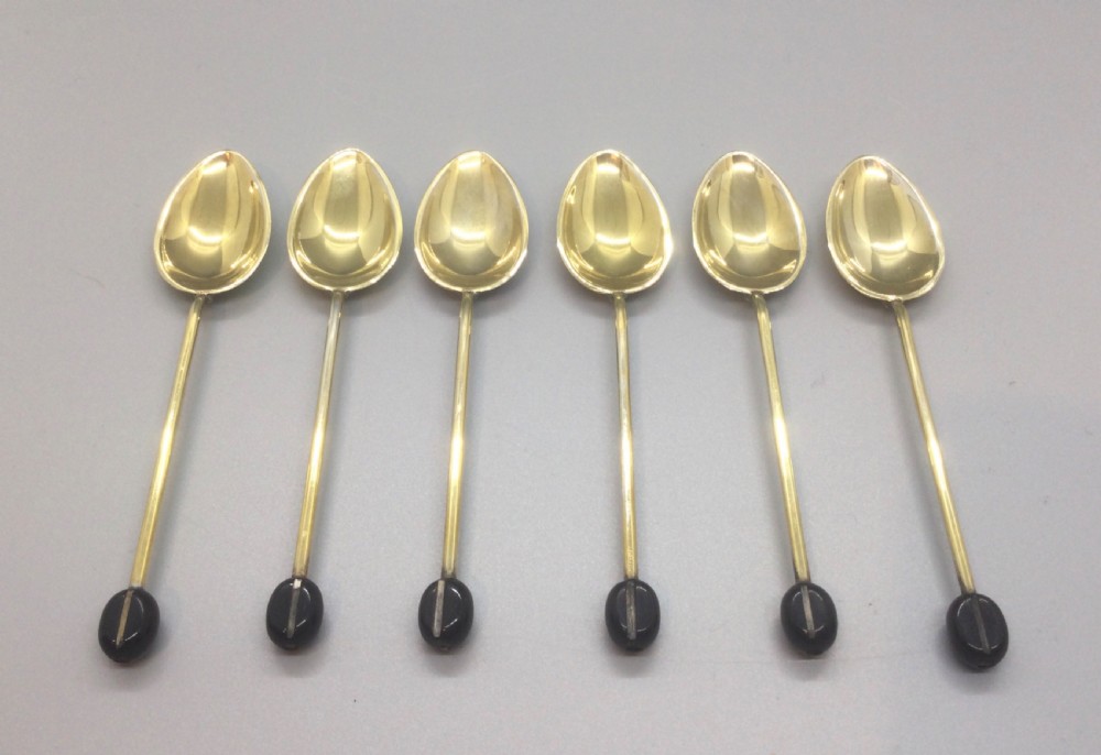 A set of six Art Deco silver gilt coffee spoons featuring colourful guilloche enamel backs, presented in a black velvet-lined case. View VI
