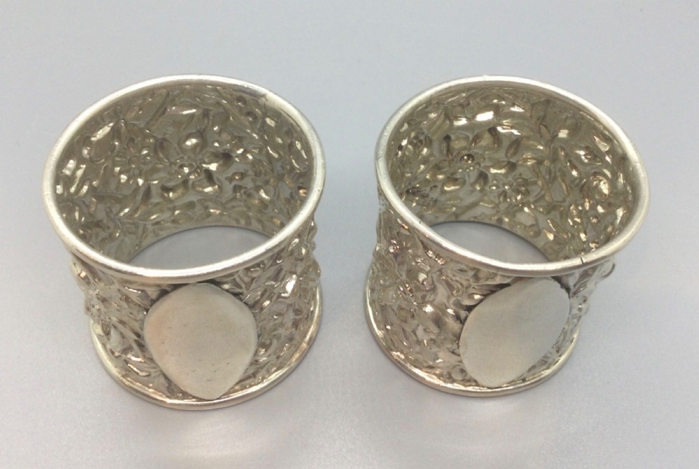 A pair of cased Victorian sterling silver napkin rings with chased floral decoration and plain oval cartouches. View IV