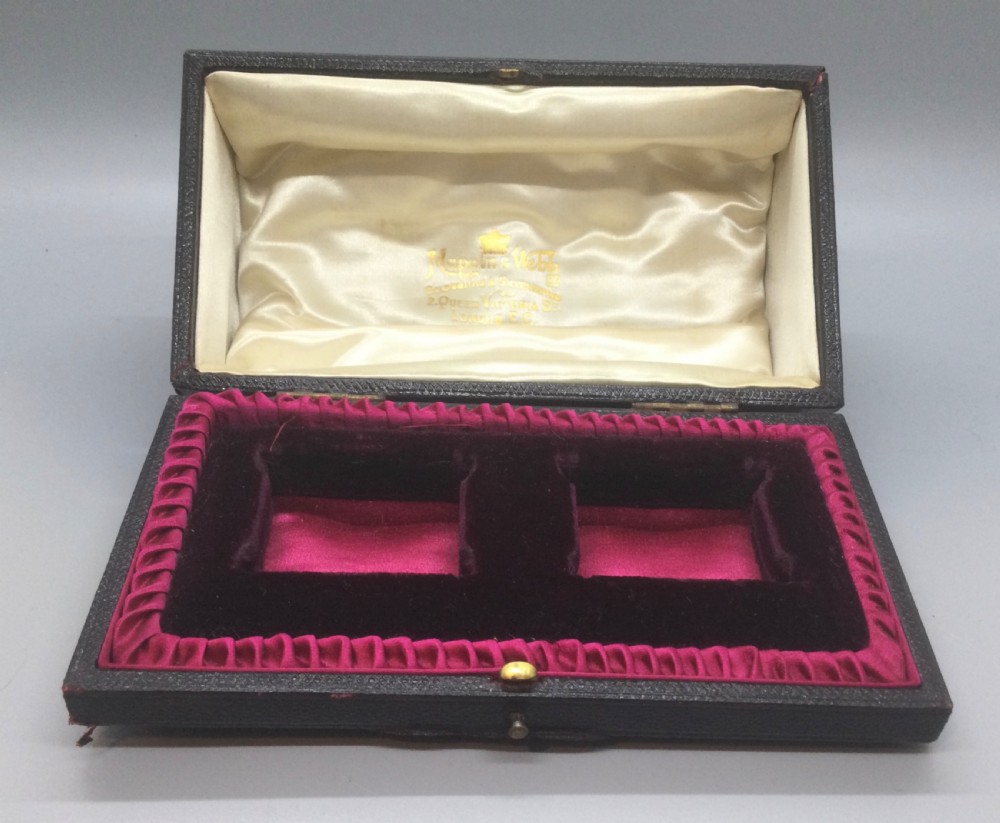 A pair of cased Victorian sterling silver napkin rings with chased floral decoration and plain oval cartouches. View IX