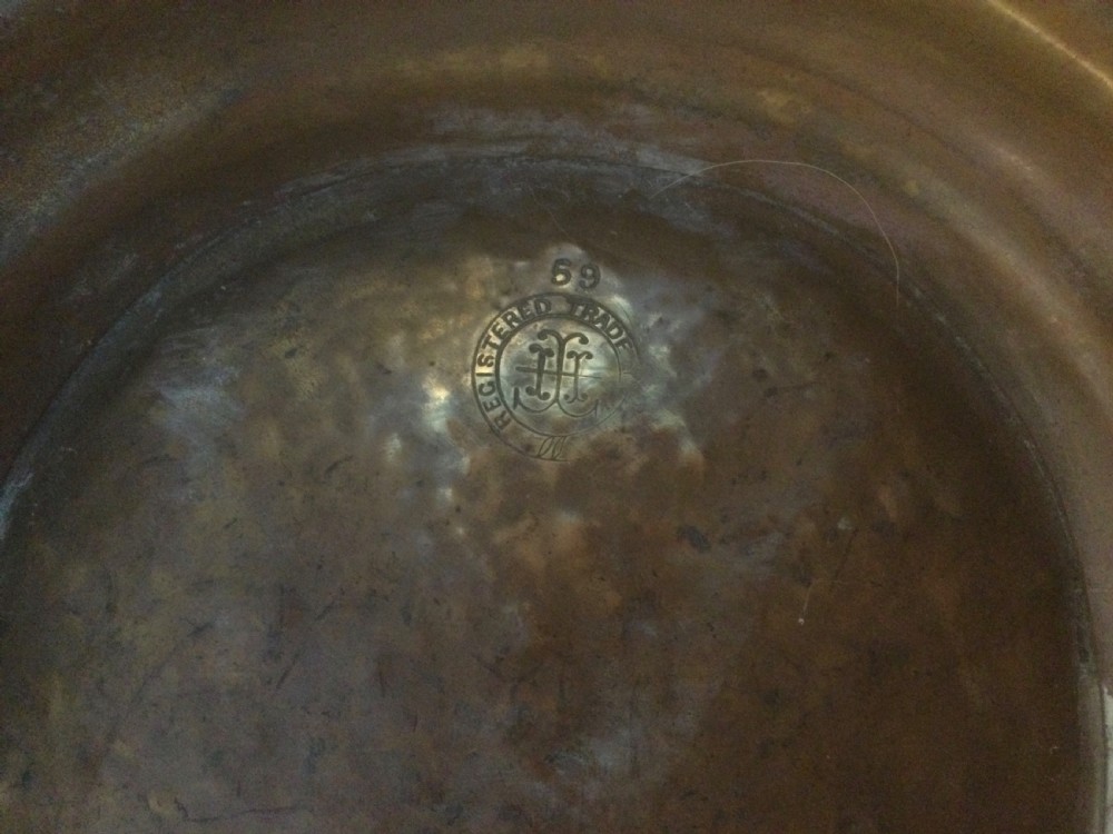 A Victorian brass helmet-shaped coal bucket featuring embossed floral details on the hood, a hammered body, swing handle, and pedestal base. View IX