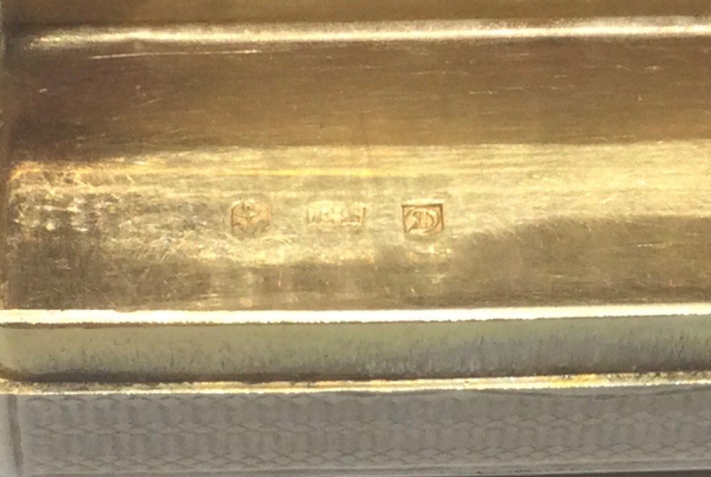 A rectangular Georgian sterling silver snuff box displaying geometric engine-turned engraving, a plain rectangular cartouche, and a chased silver thumbpiece. View X
