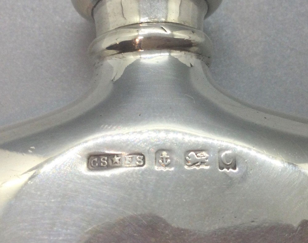 A smooth, polished sterling silver pocket flask with a contoured body and rounded screw cap against a neutral backdrop. View VII