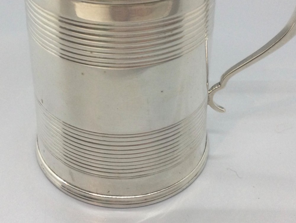 A cylindrical sterling silver christening mug featuring horizontal reeded banding and an angular curved handle. View VI