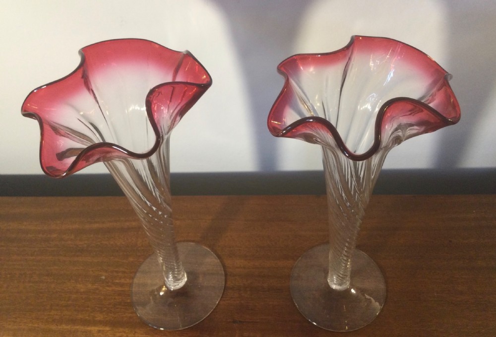 A pair of tall Art Nouveau glass trumpet vases featuring flared, ruffled cranberry rims and clear spiral-twisted stems on round bases. View II