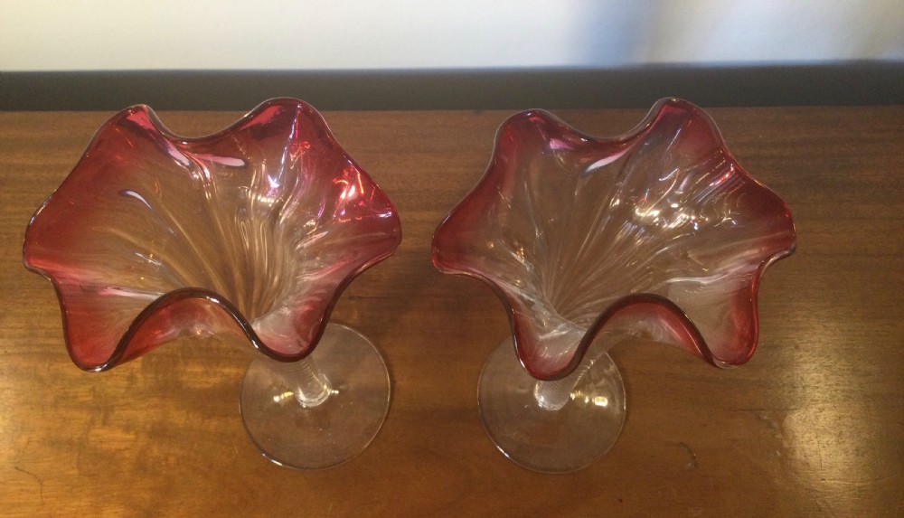 A pair of tall Art Nouveau glass trumpet vases featuring flared, ruffled cranberry rims and clear spiral-twisted stems on round bases. View V
