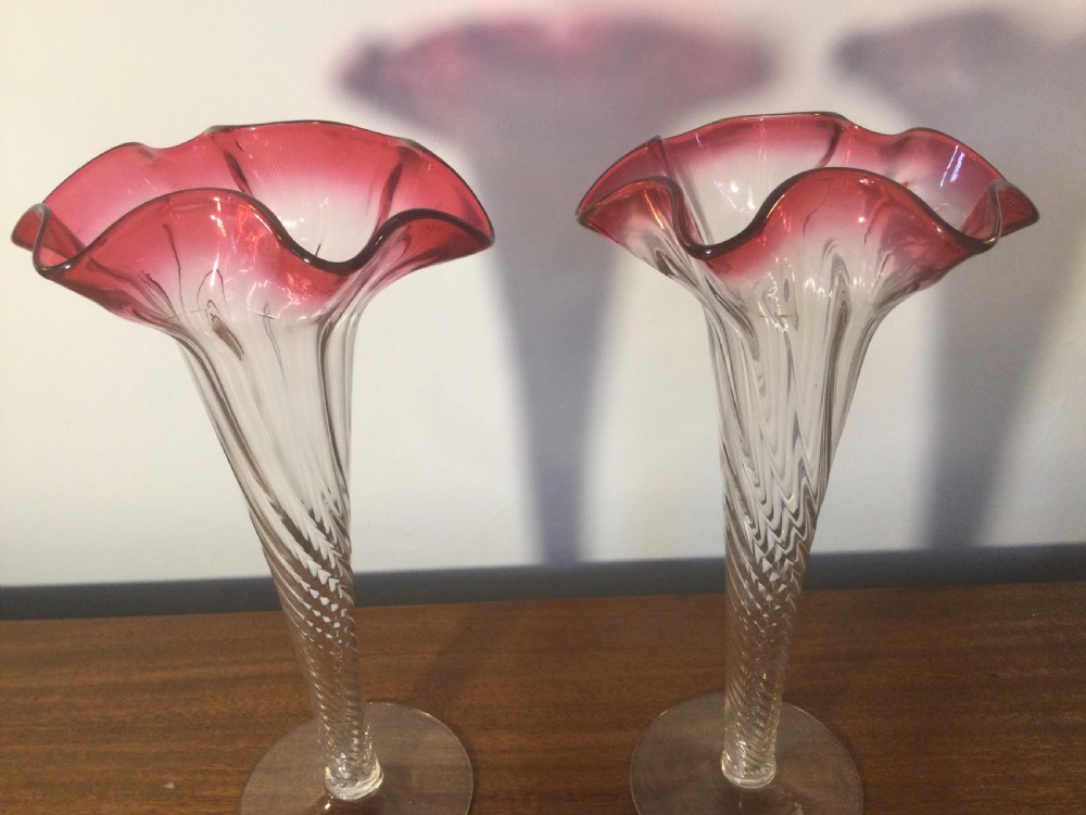 A pair of tall Art Nouveau glass trumpet vases featuring flared, ruffled cranberry rims and clear spiral-twisted stems on round bases. View VII