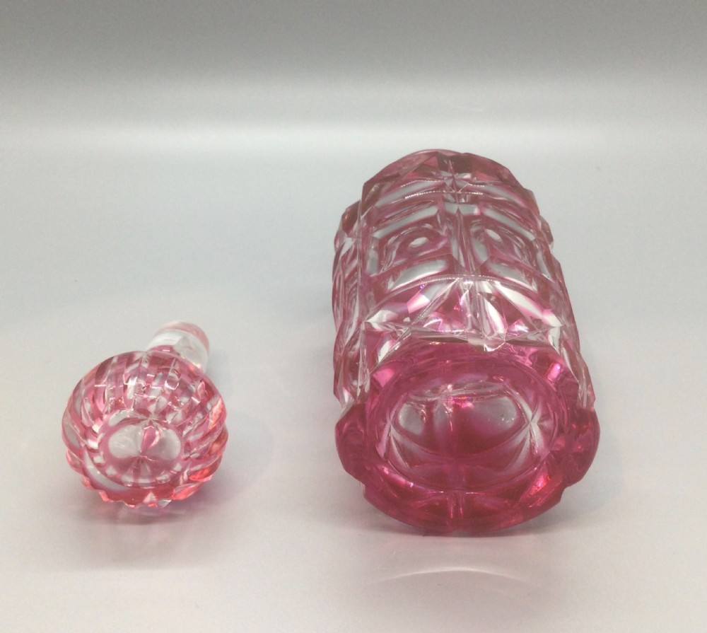 A Victorian cranberry overlay cut glass scent bottle with geometric cross-cut patterns and a faceted glass stopper. View VI