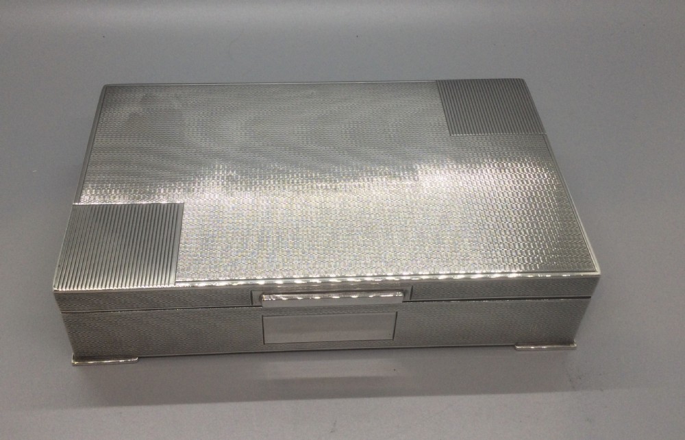 A rectangular sterling silver Art Deco box featuring an engine-turned geometric pattern and a small cartouche on the front edge.