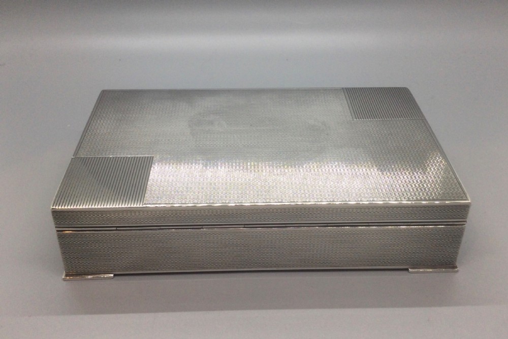 A rectangular sterling silver Art Deco box featuring an engine-turned geometric pattern and a small cartouche on the front edge. View VI