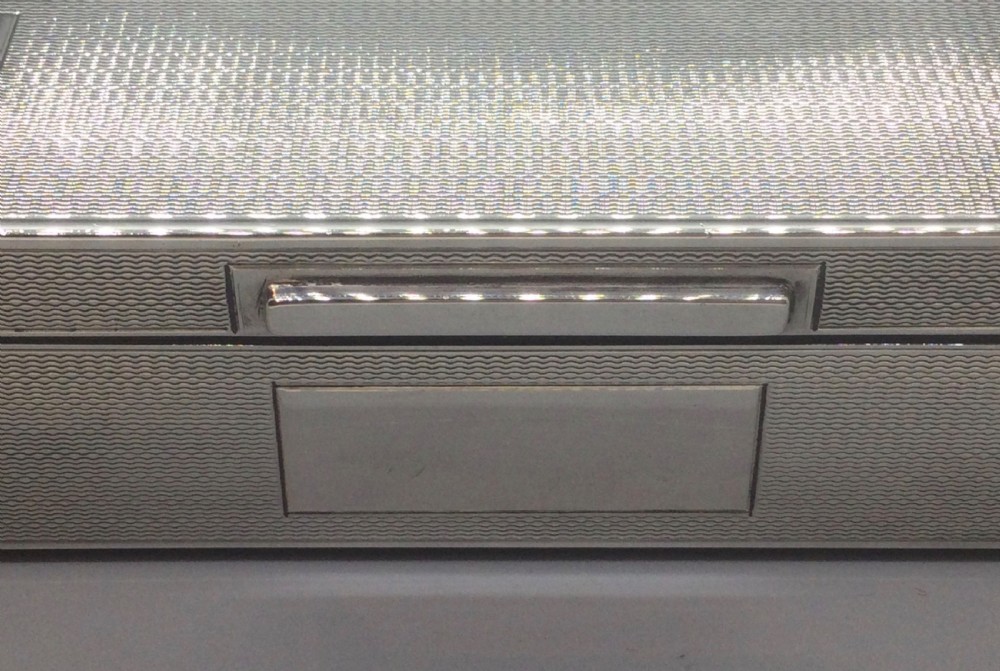 A rectangular sterling silver Art Deco box featuring an engine-turned geometric pattern and a small cartouche on the front edge. View X