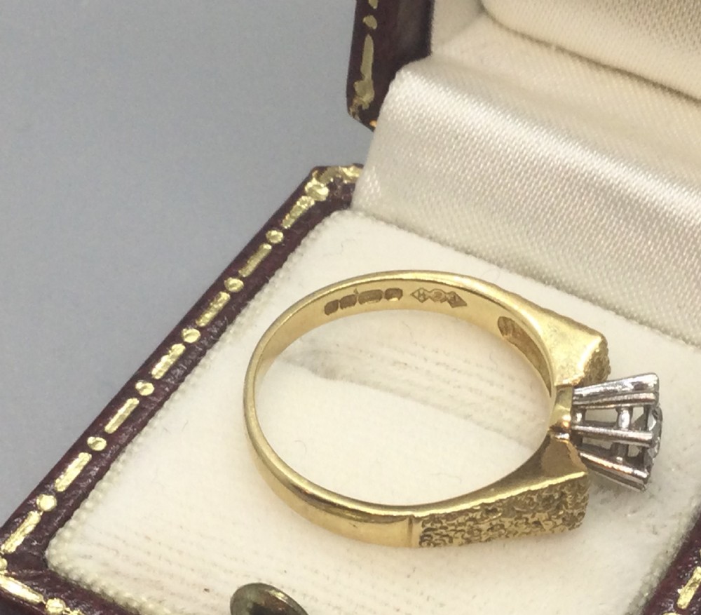 A vintage 18ct yellow gold solitaire ring featuring a textured bark-effect band and a central diamond in a claw setting. View V
